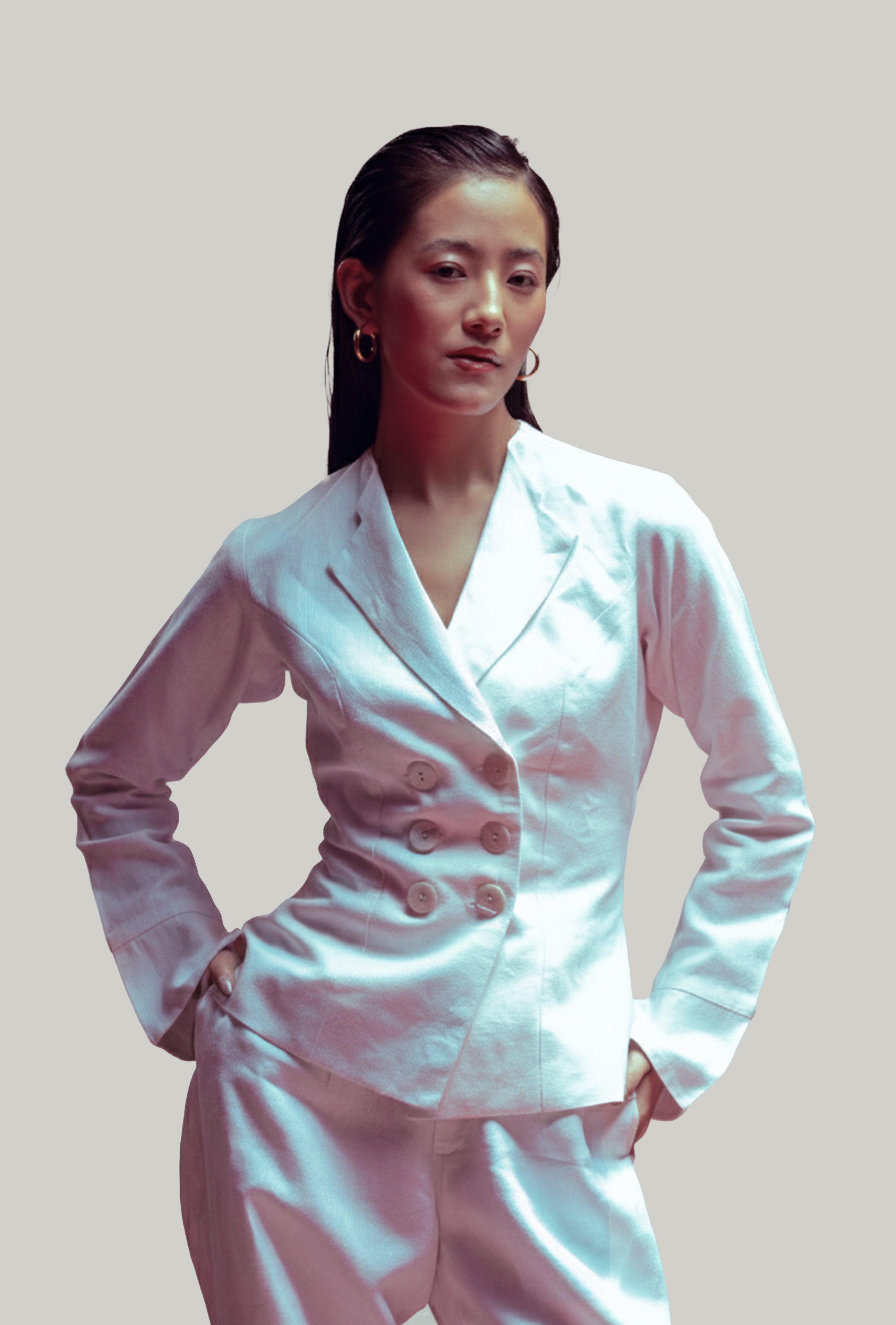 Woman wearing a white suit against a plain background