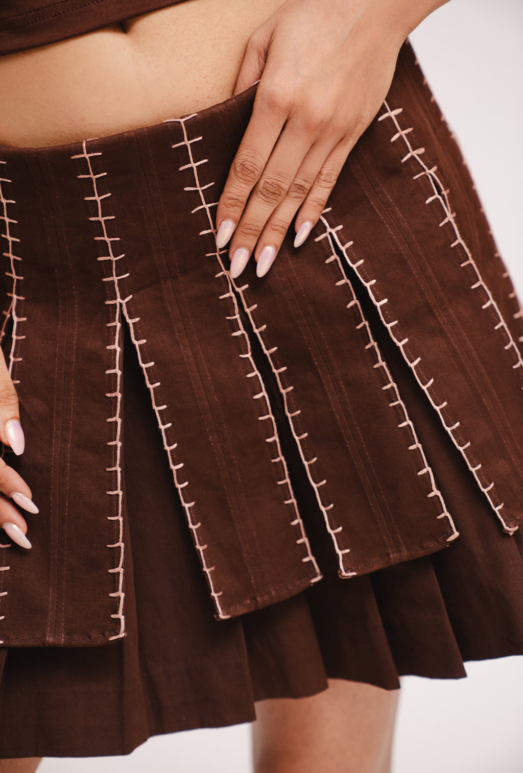 Brown skirt with white stitching detail worn by a person.