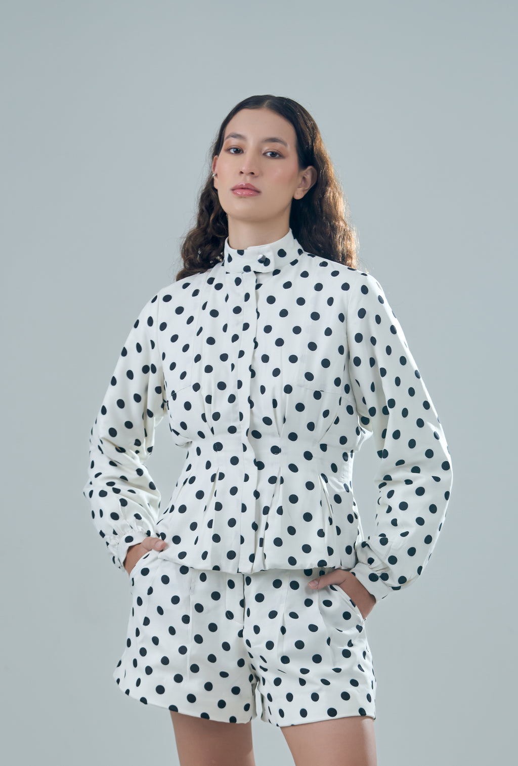 Person wearing a polka dot outfit on a gray background