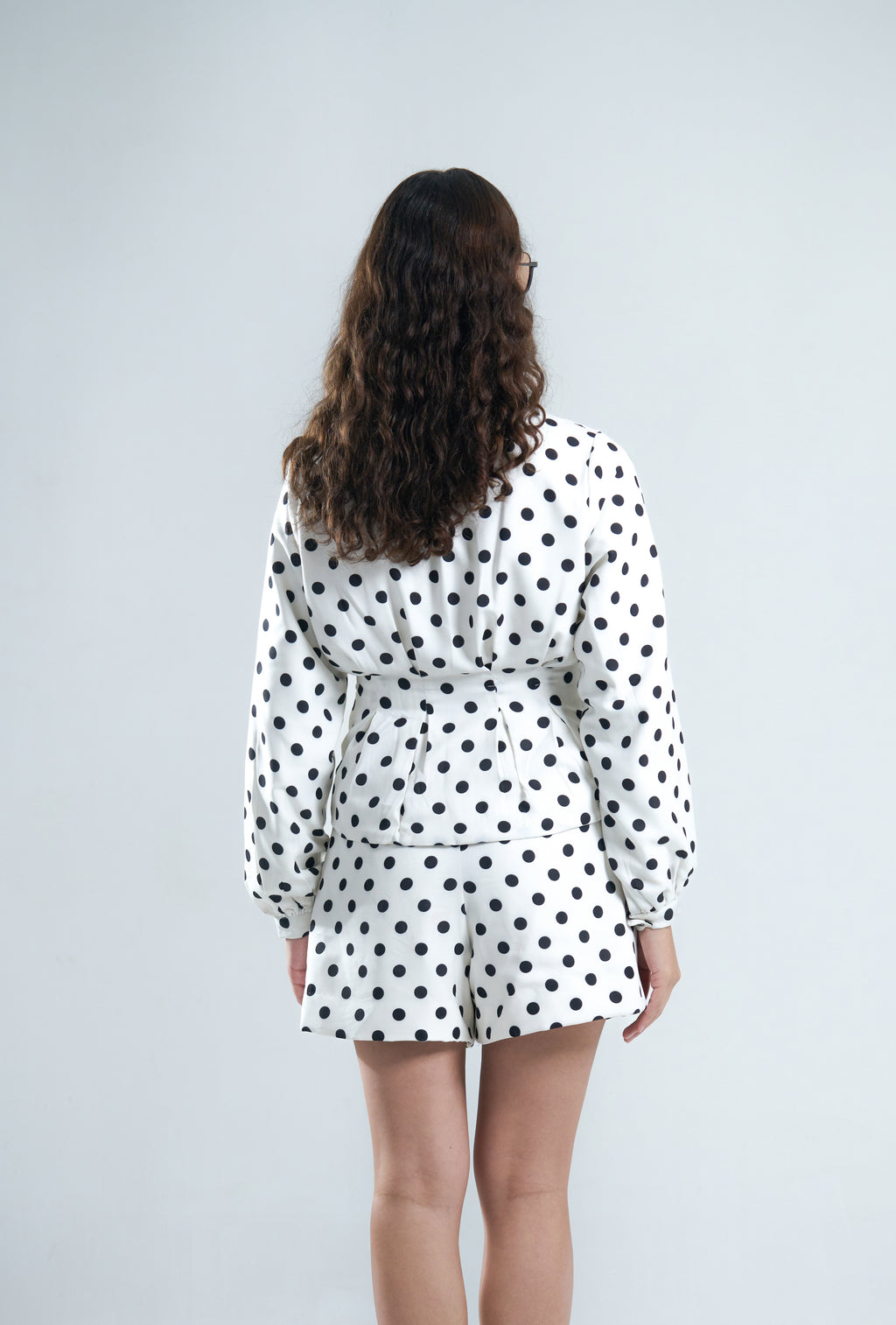 Woman wearing a polka dot outfit on a plain background