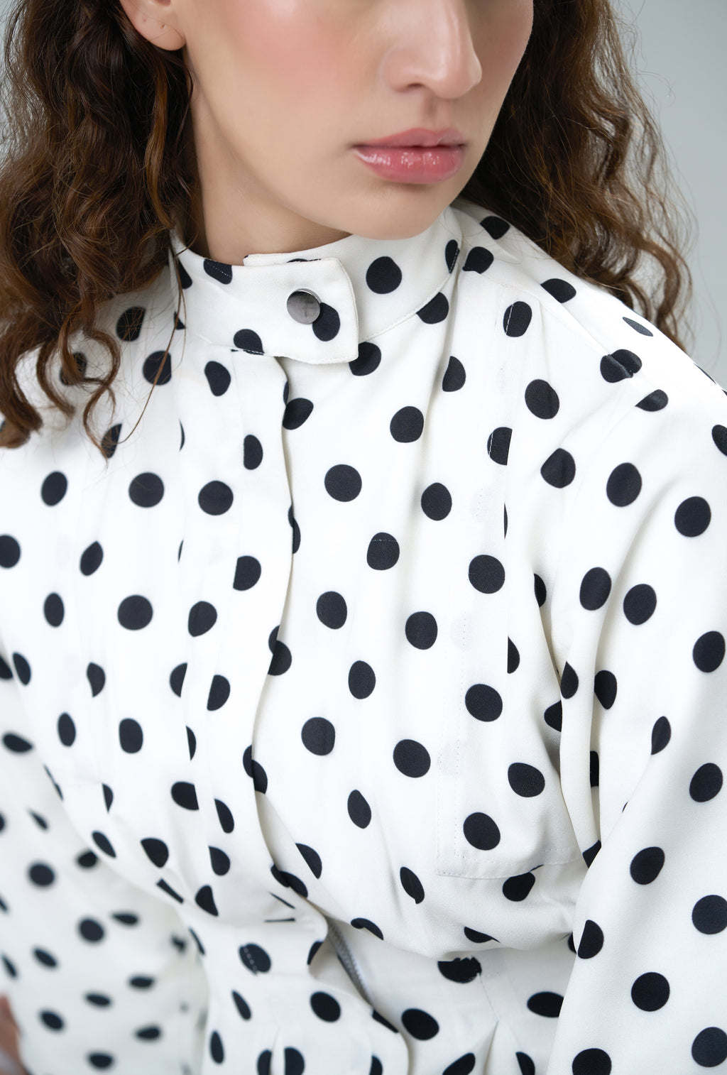 Person wearing a white jacket with black polka dots